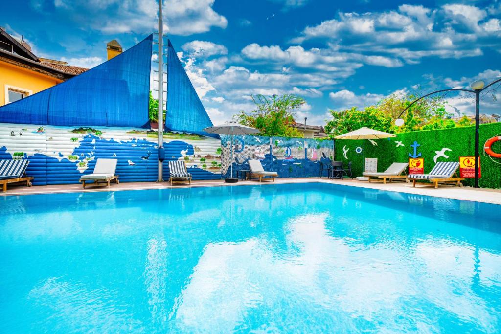 戈西克Dedeminn Garden Hotel的一个带椅子和遮阳伞的大型蓝色游泳池