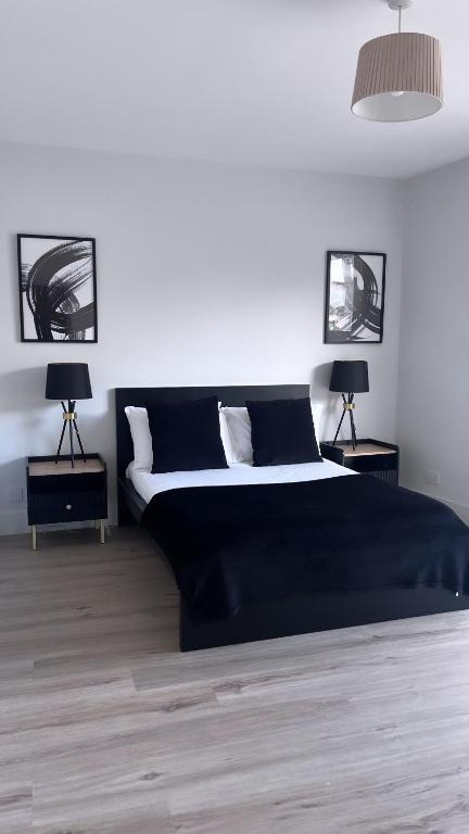 格拉斯哥3 Bedroom House Near City Centre Glasgow Sleeps 7的一间卧室配有一张带两盏灯的大型黑色床。