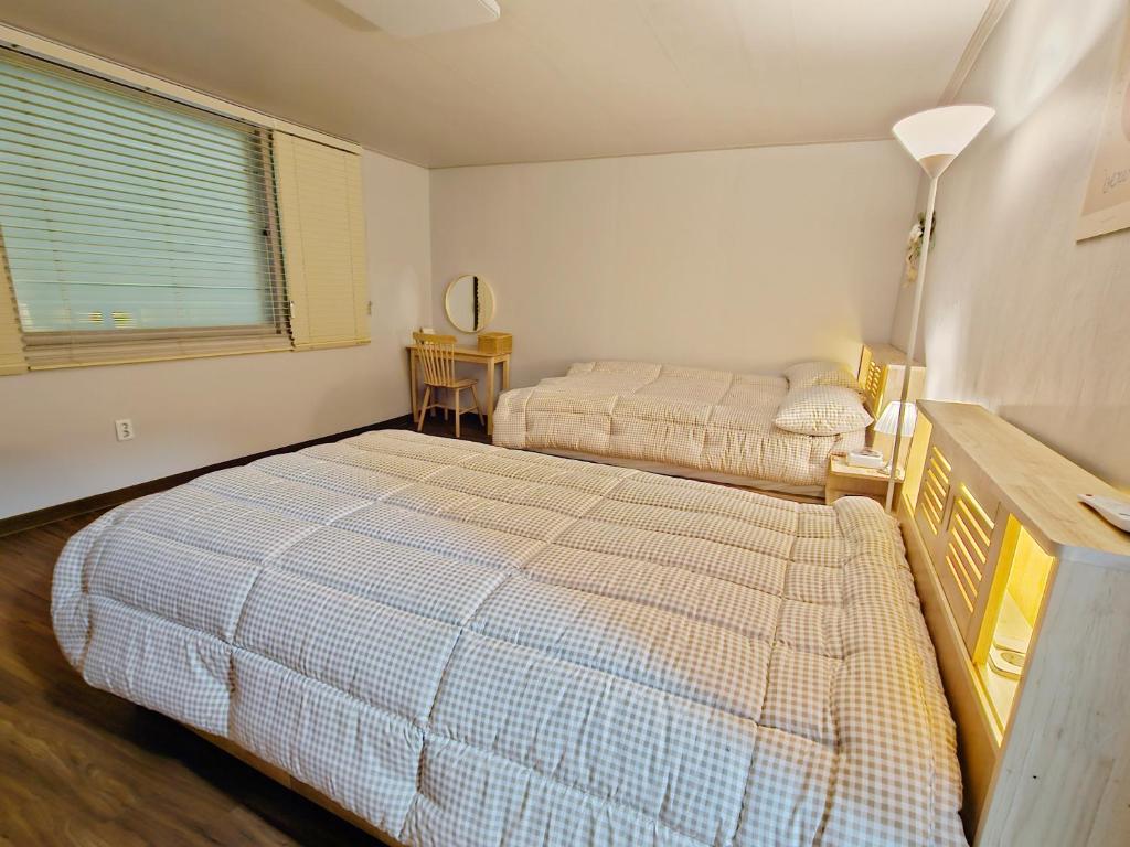 江陵市Happy Jumunjin House的一间卧室配有两张床和一盏灯。