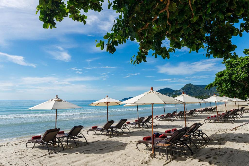 查汶Anavana Beach Resort的海滩上的一组椅子和遮阳伞