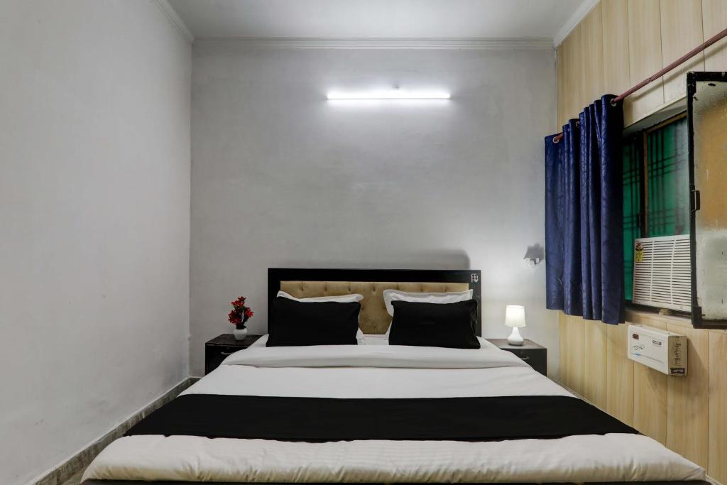 勒克瑙OYO Flagship Dripp Stay Inn的一间卧室配有一张带蓝色窗帘的大床