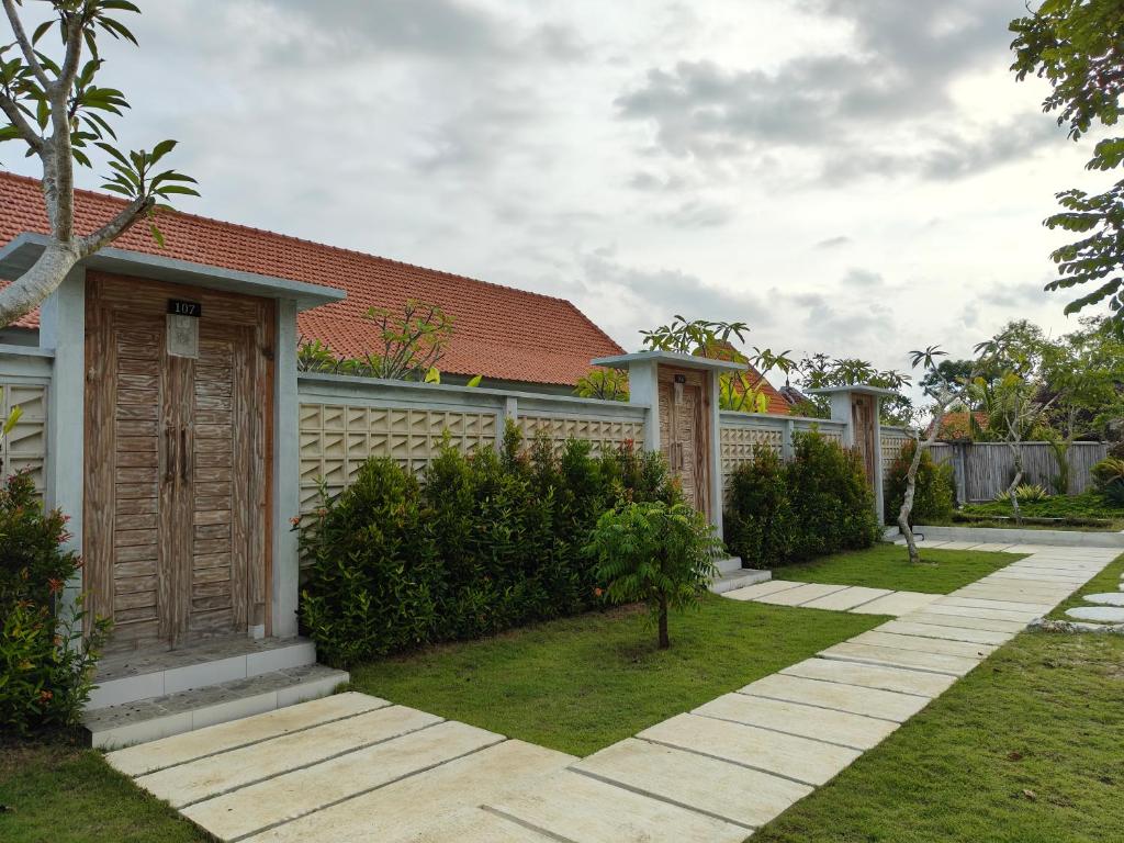 乌鲁瓦图Alam Cottage Uluwatu的一座带栅栏和草地庭院的房子