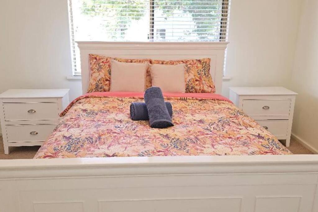 珀斯Peaceful House的一间卧室配有一张带两个白色床头柜的床