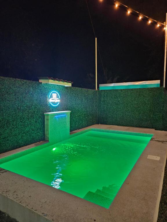 别霍港Ocean's Breeze Apartment and Rooms的游泳池在晚上提供绿色照明