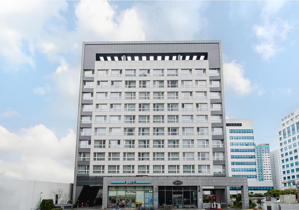 昌原市Grand City Hotel Changwon的一座高大的白色建筑,有很多窗户