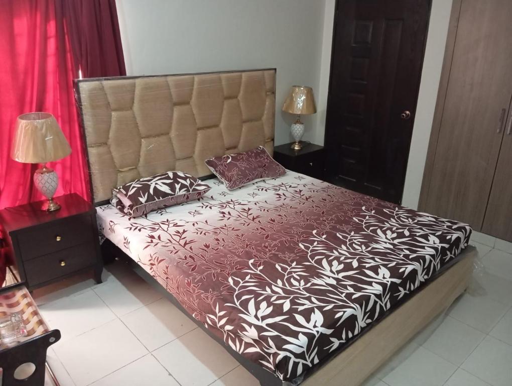 拉合尔Balqees Cottage的卧室配有一张大床,提供红白床单和枕头。