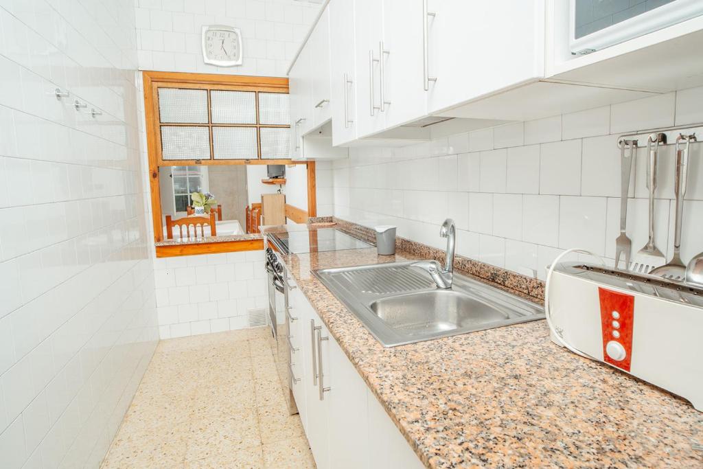 LariñoApartamentos Ancoradoiro的白色的厨房设有水槽和窗户