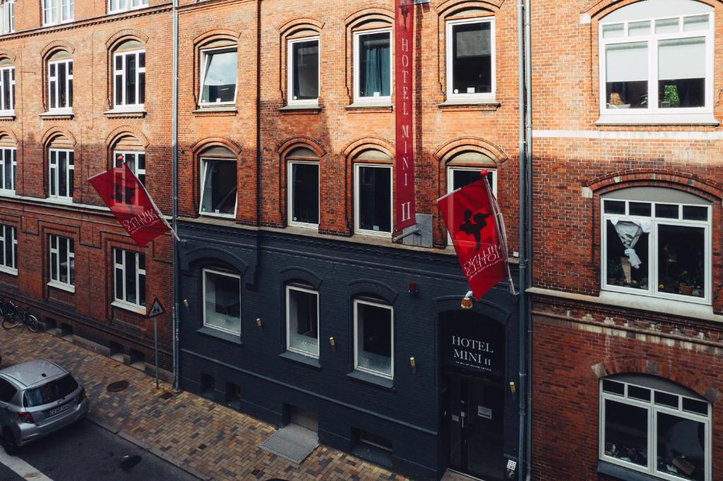 欧登塞Milling Hotel Mini 11的建筑物一侧有两面红旗