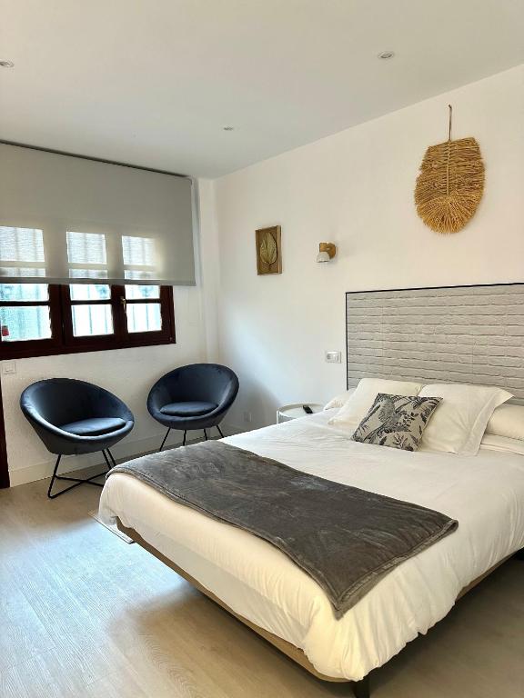 柯米拉斯Apartamentos Val de Comillas的一间卧室配有一张大床和两把椅子