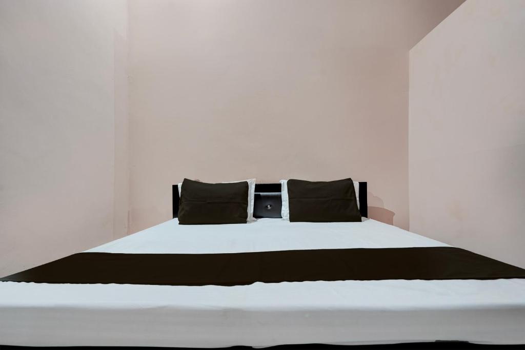 BulandshahrSPOT ON guest house的一张白色的床,上面有黑色枕头