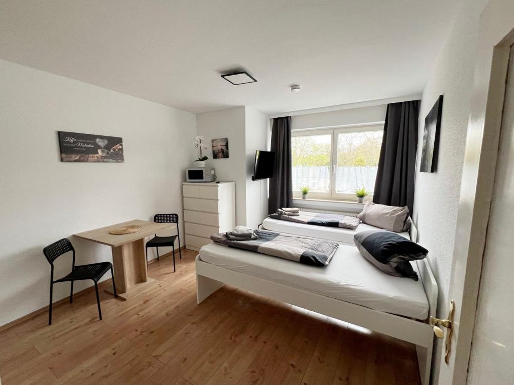 科隆Low Budget Apartment Cologne的一间卧室设有两张床、一张桌子和一个窗口。