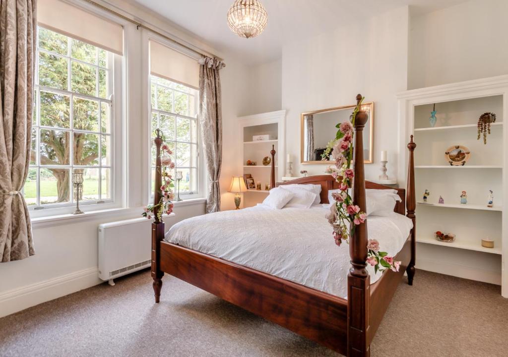 StradsettThe Lake House - Crimplesham Hall的一间卧室设有一张床和两个窗户。