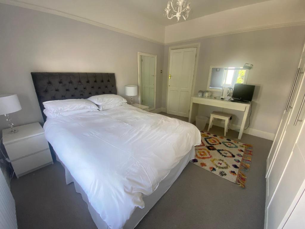 HadleighRooms in Hadleigh,Essex的卧室配有一张白色大床和一张书桌