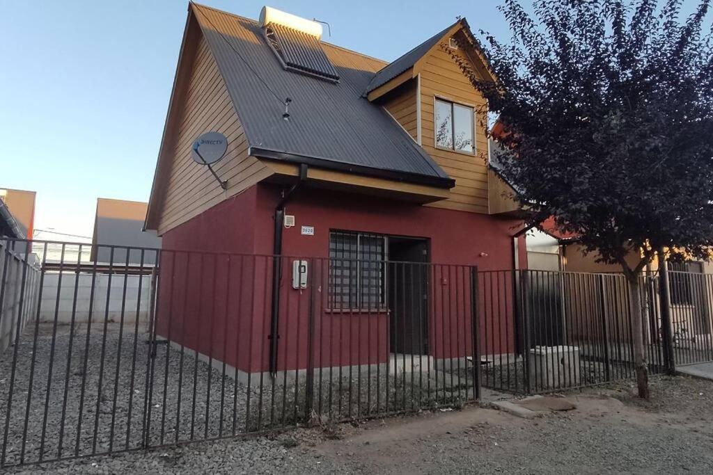塔尔卡Cómoda casa en Talca的一座红色的房子,有黑色的屋顶和栅栏