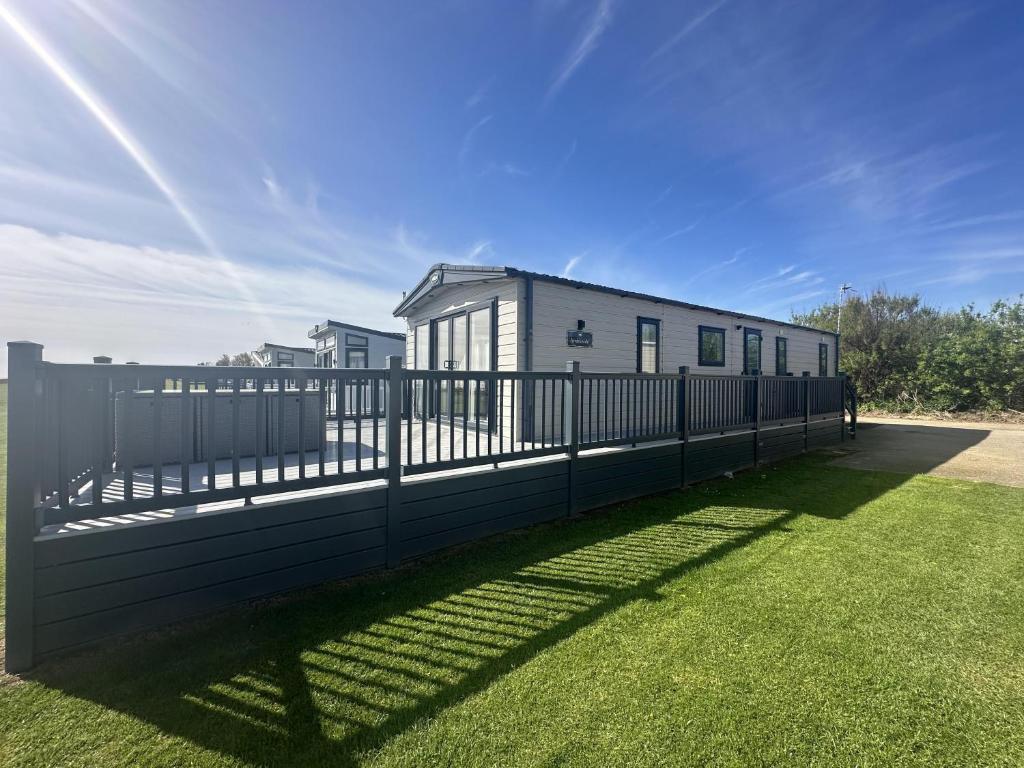 Hopton on SeaLuxury Lodge With Stunning Full Sea Views In Suffolk Ref 20234bs的院子内有黑色的围栏,有房子