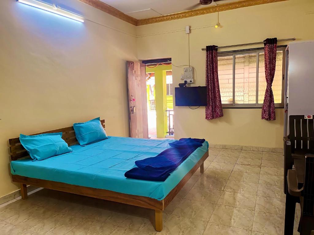 马尔万Coco Hut , Devbaug的一间卧室配有一张带蓝色床单的床和一扇窗户。