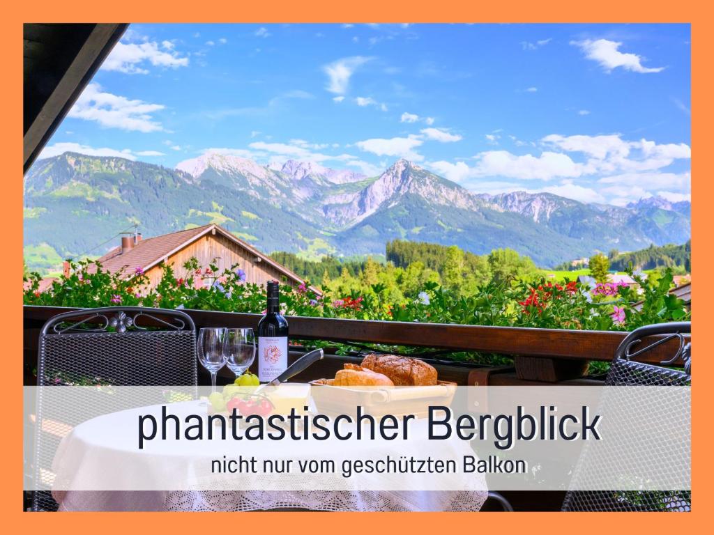 博尔斯特尔朗Biohof Burger, 3 sonnige Fewo, alle mit Balkon, Spielzimmer, Grillhütte, 7 km vor Oberstdorf的一张桌子,上面放着一杯葡萄酒,享有山景