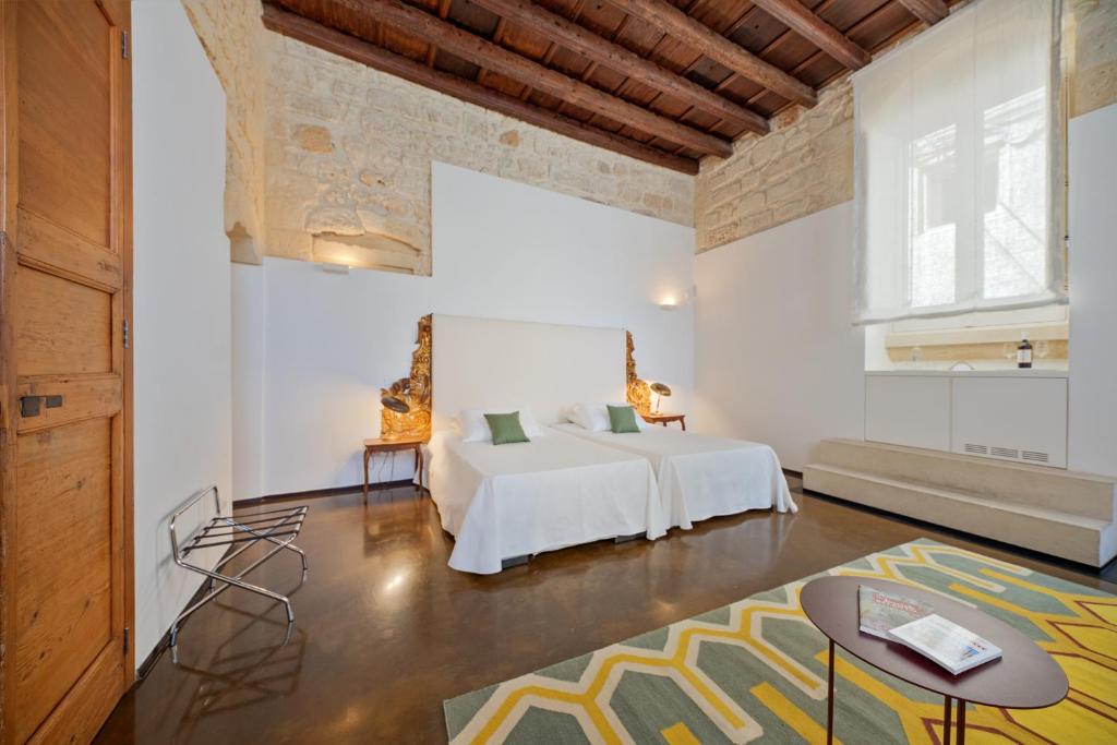 莱切Palazzo Personè Dimora Storica的卧室配有一张床铺,位于带桌子的房间