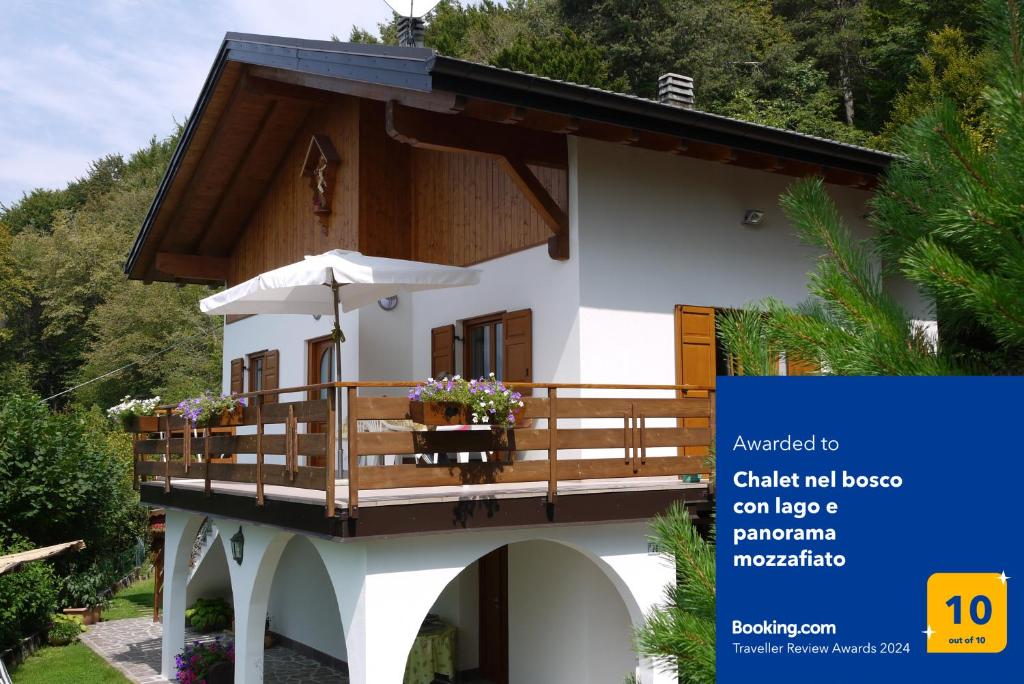 Lagolo di CalavinoChalet nel bosco con lago e panorama mozzafiato的一个小房子,带有阳台,配有雨伞