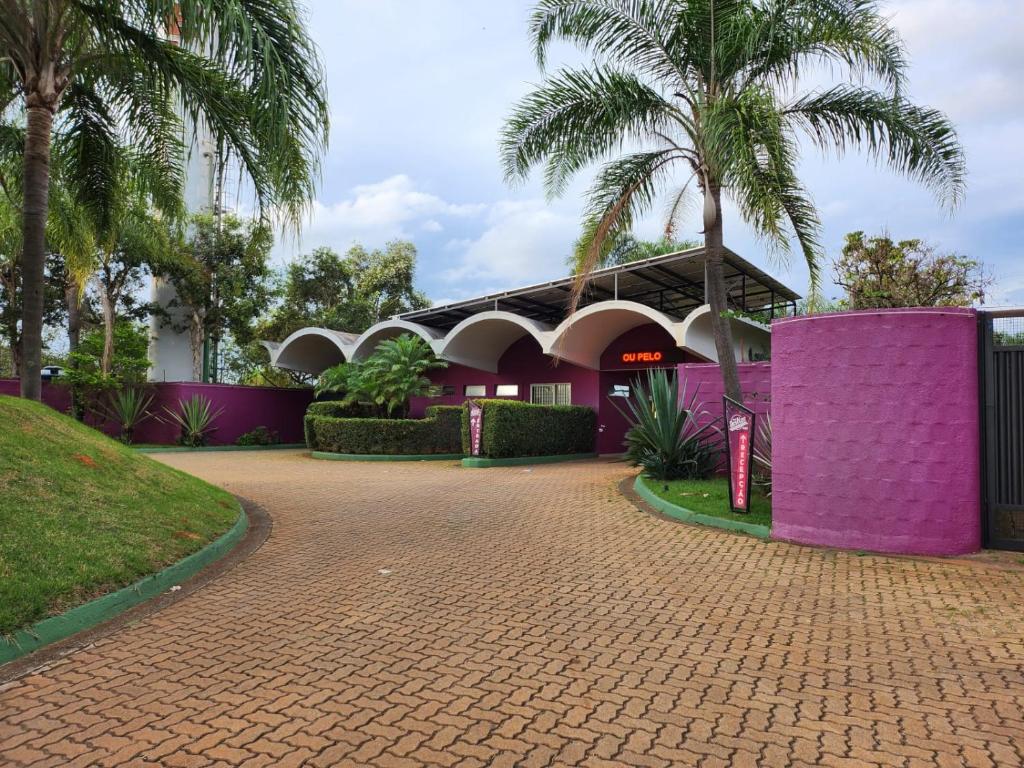 里梅拉Motel Deslize Limeira 3的一座紫色墙壁和棕榈树的建筑