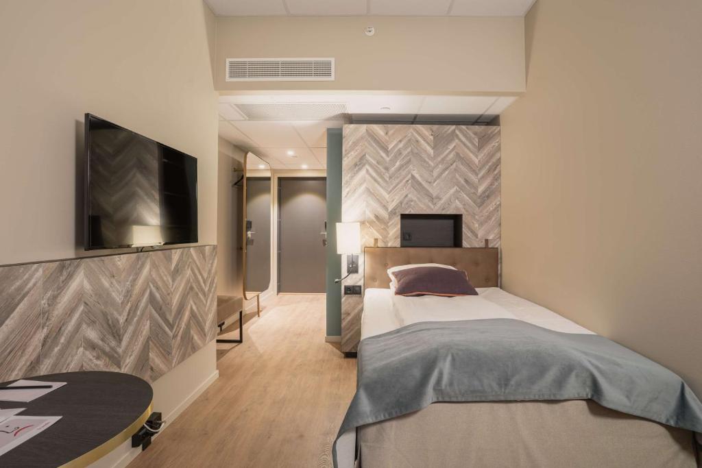特罗姆瑟特罗姆瑟斯堪迪豪华酒店的一间卧室配有一张床和一台平面电视