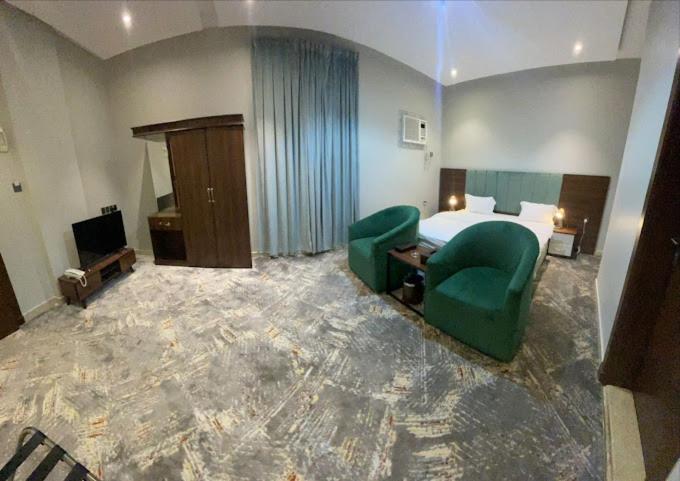 Sīdī Ḩamzahأضواء الشرق للشقق الفندقية Adwaa Al Sharq Hotel Apartments的酒店客房,配有一张床和两张绿色椅子