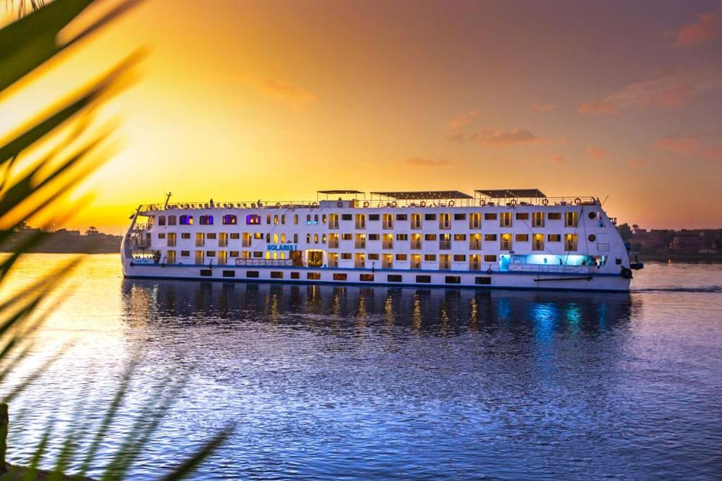 Aḑ Ḑab‘īyahNile Cruise luxury boat Every Saturday From Luxor & Every Wednesday from Aswoan的日落时分在水面上的大型游轮