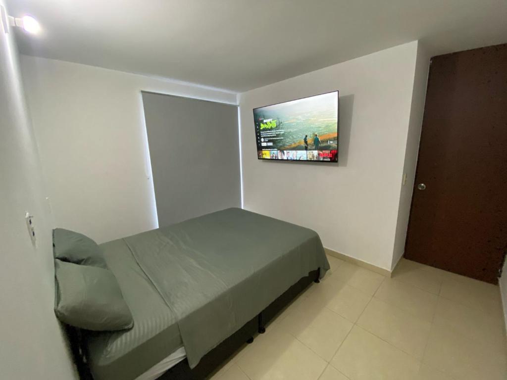 库库塔Habitación en Apartamento amplio cómodo y equipado的卧室配有一张床,墙上配有电视。