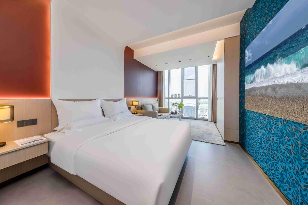 昆明愈熙高空智能酒店(昆明高铁南站店)的一张大白色的床,位于一个有大画的房间里