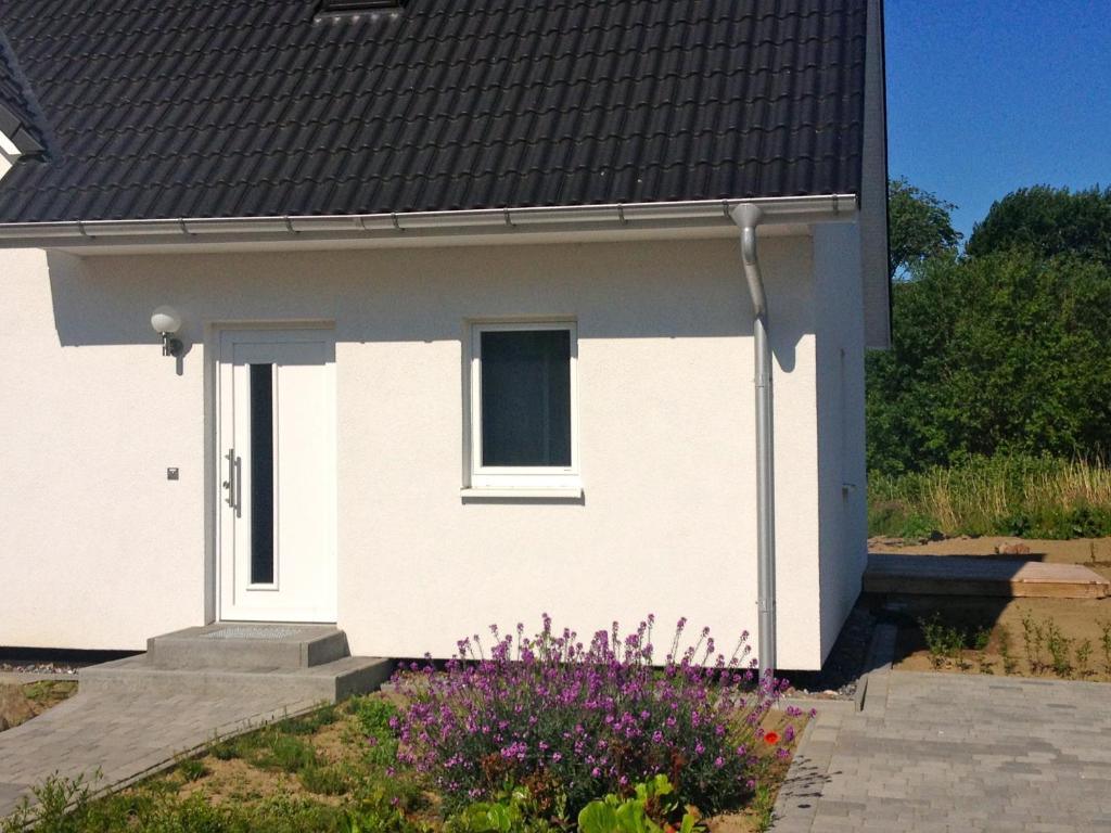 PatzigFerienwohnung in Patzig auf Rügen的白色的房子,有窗户和一些鲜花