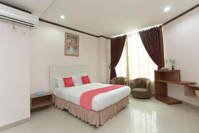贝努阿亚尔Hotel Kharisma的一间卧室配有一张带红色枕头的大床