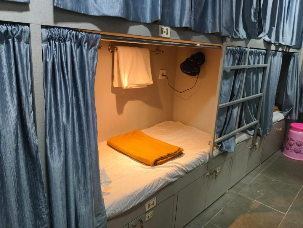 孟买Rest Inn Hostel Dormitory的一张小床,位于带蓝色窗帘的房间