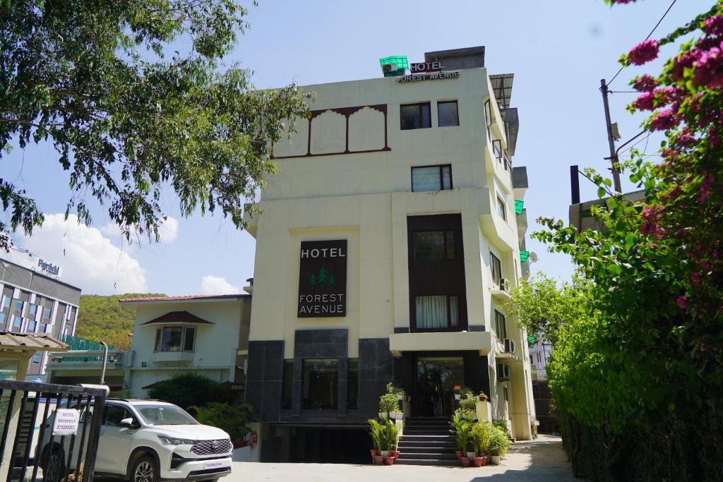 德拉敦Hotel Forest Avenue - Best Luxury Hotel in Dehradun的白色的建筑,上面有标志