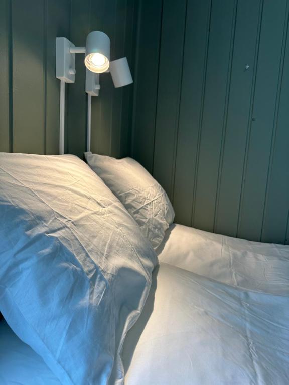 利勒斯特罗姆KM Rentals - Lillestrøm City - Private Rooms in Shared Apartment的一张铺有白色床单的床和墙上的灯