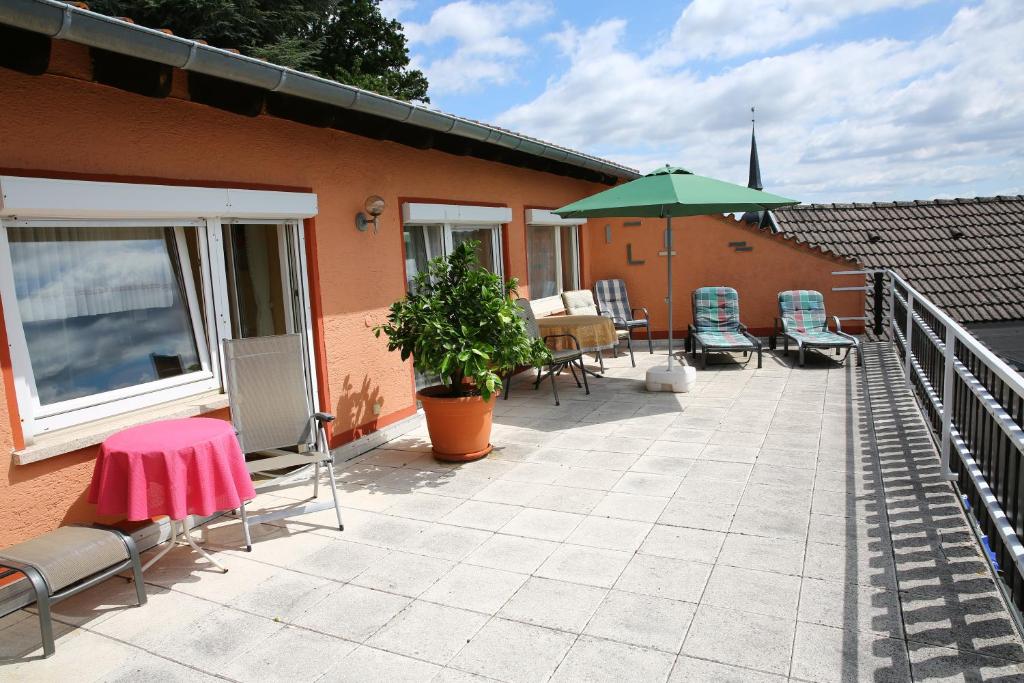 GleisweilerPension Weinberg mit Landhaus Nizza的庭院配有桌椅和遮阳伞。