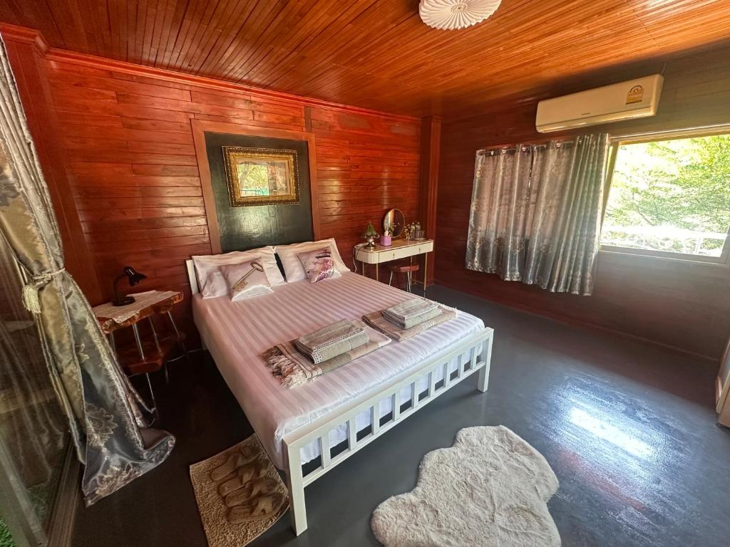Ta Phrayaไททำดี โฮมสเตย์ Taitam-D Homestay的木制客房内的一间卧室,配有一张床
