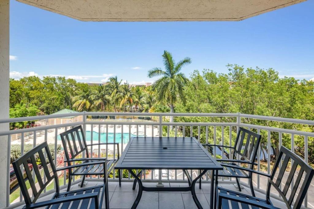 基韦斯特The Barbados by Brightwild-Bright Condo w Pool的一个带桌椅的阳台和一个游泳池