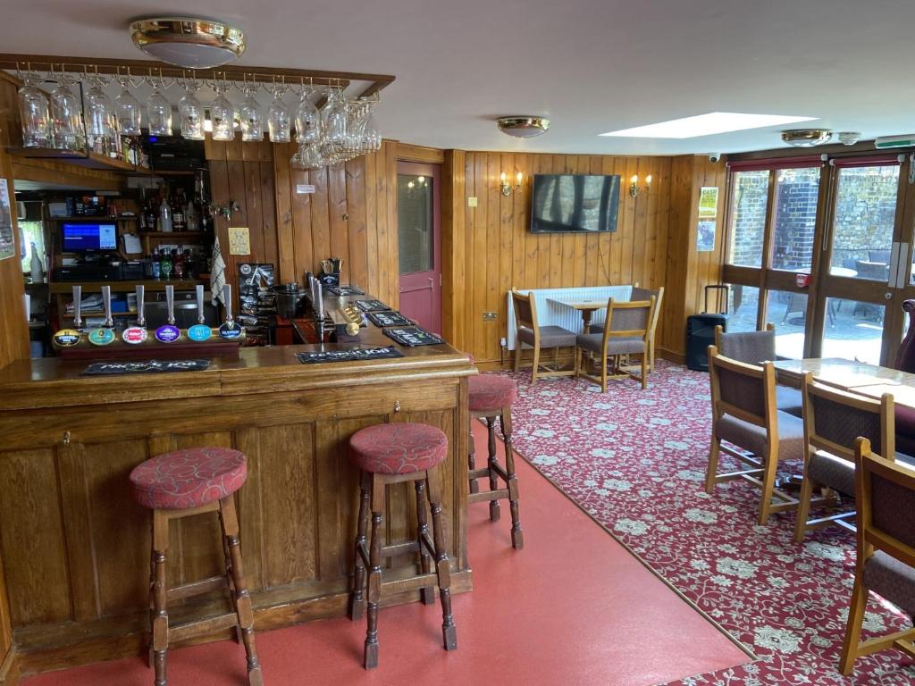 格雷夫森德The Jolly Drayman Pub and Hotel的餐厅内的酒吧配有桌椅