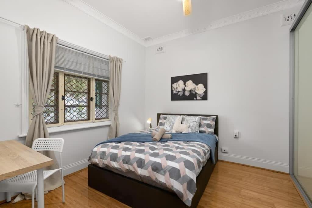 悉尼Lidcombe Boutique Guest House near Berala Station3的一间卧室配有一张床、一张桌子和一个窗户。