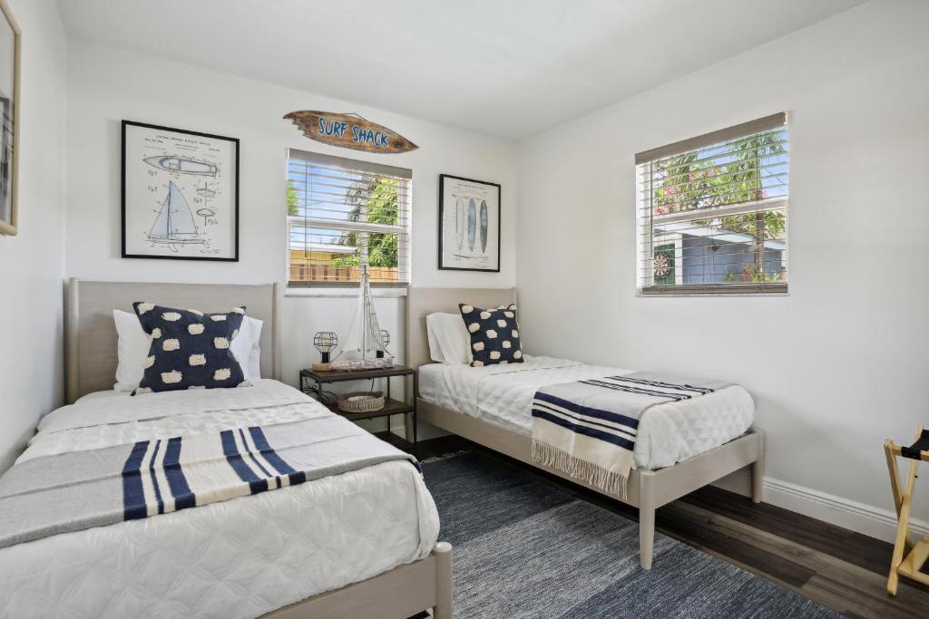 波因顿海滩Tiki Hut的一间卧室设有两张床和两个窗户。