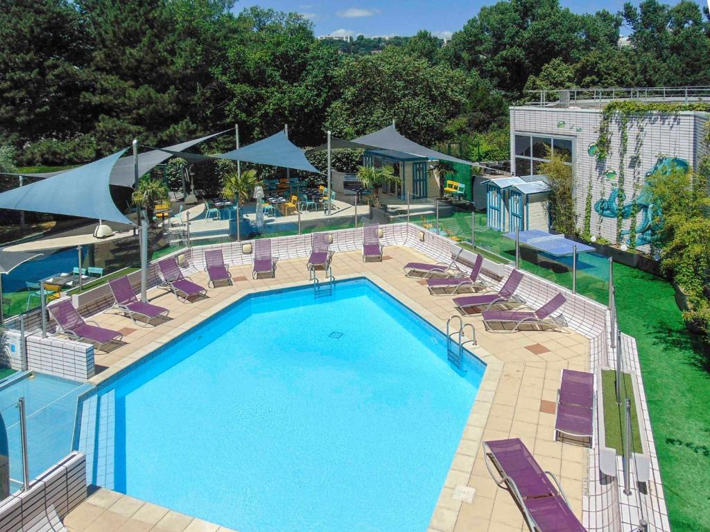 里昂里昂热尔兰博物馆诺富特酒店的享有带躺椅的游泳池的顶部景致