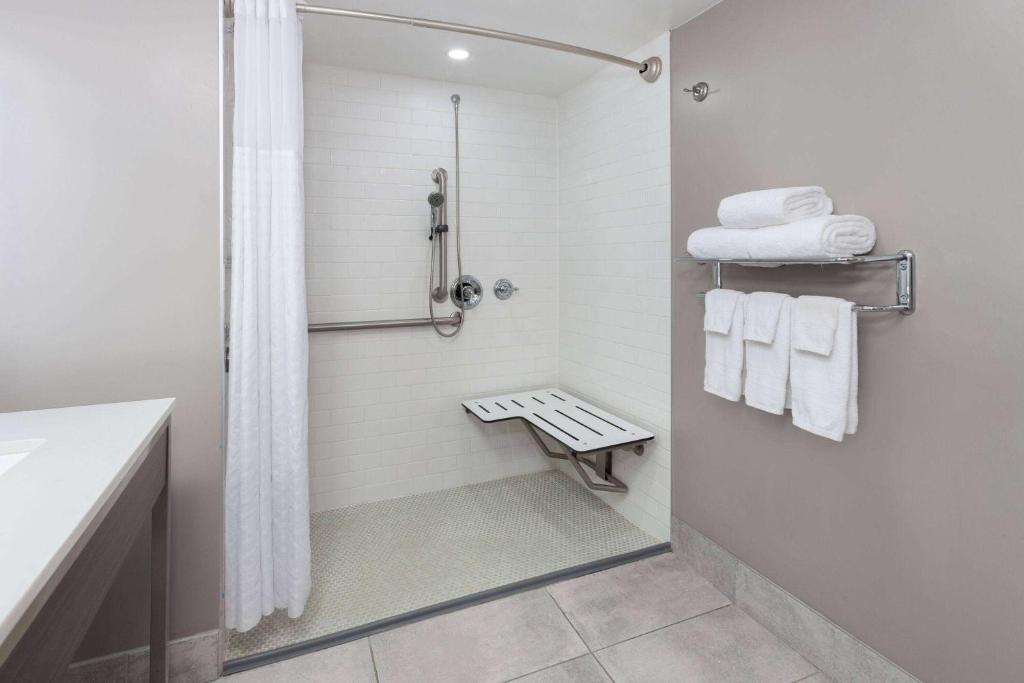 巴尔的摩Super 8 by Wyndham Baltimore Northwest的带淋浴和白色毛巾的浴室