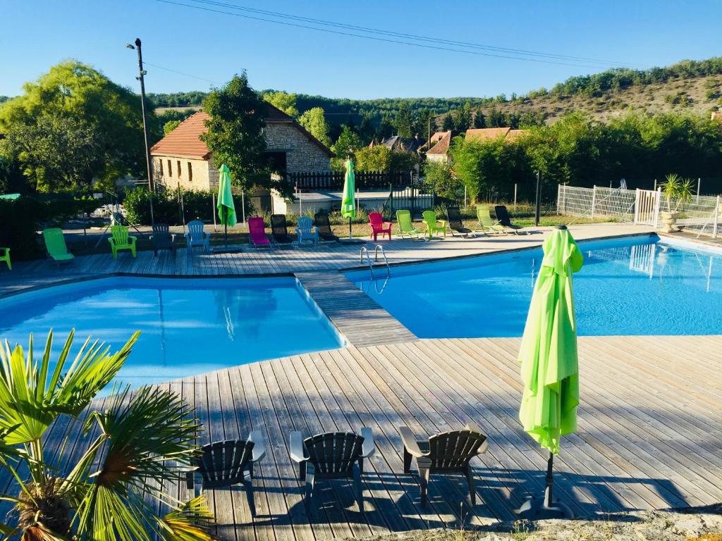 Saint-ChamarandLa Colline aux Chalets, Jaccuzi, Sauna的一个带椅子和绿色遮阳伞的游泳池