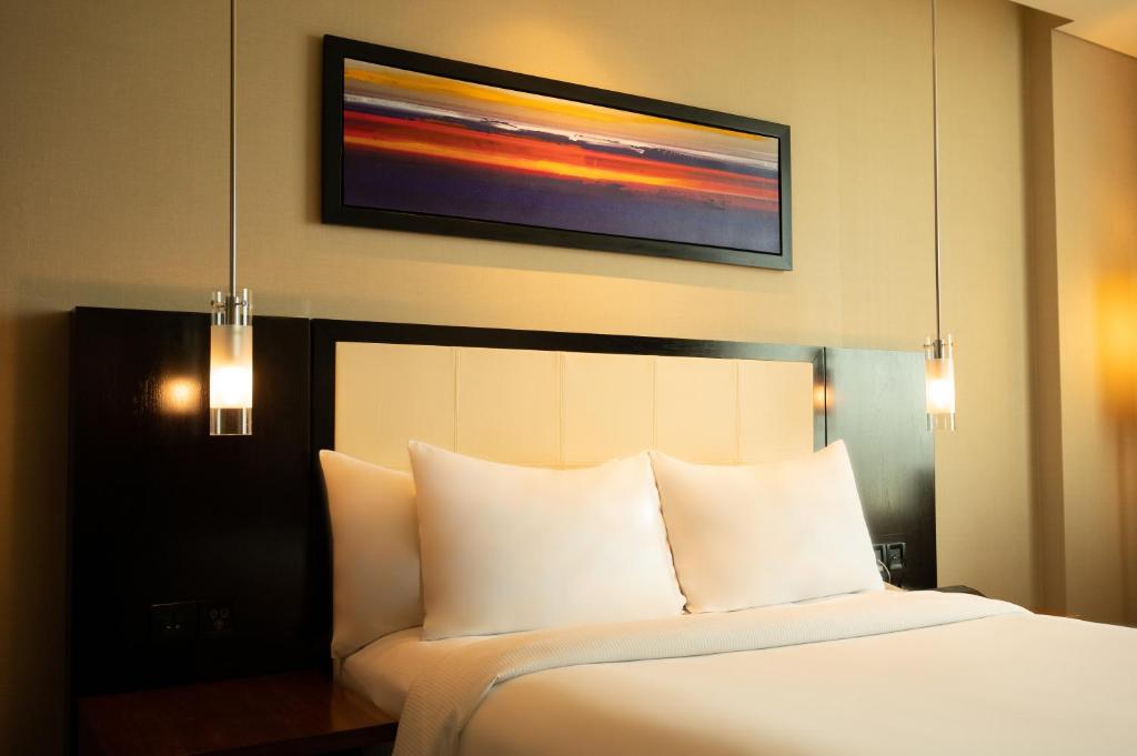 浦那DoubleTree by Hilton-Pune Chinchwad的卧室配有一张白色床,墙上挂着一幅画