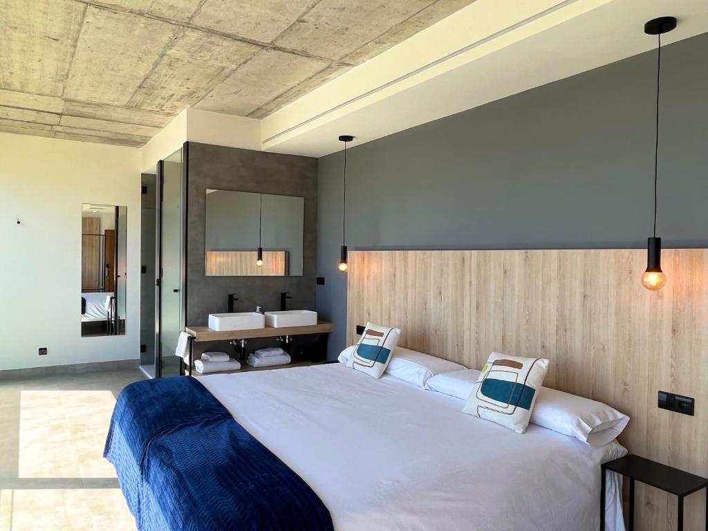 卡马里尼亚斯Hospedium Hotel Devalar Do Mar的一间带大床的卧室和一间浴室