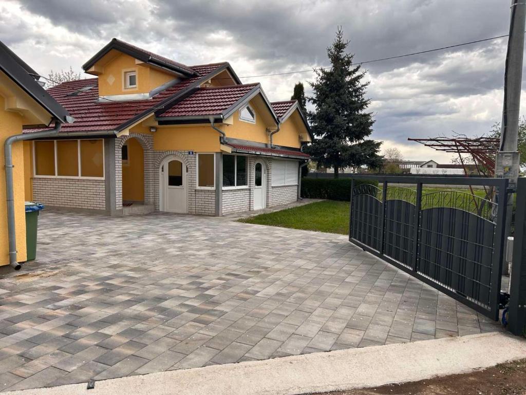 拉克塔希Vikendica Leona的黄色的房子,有栅栏和车道