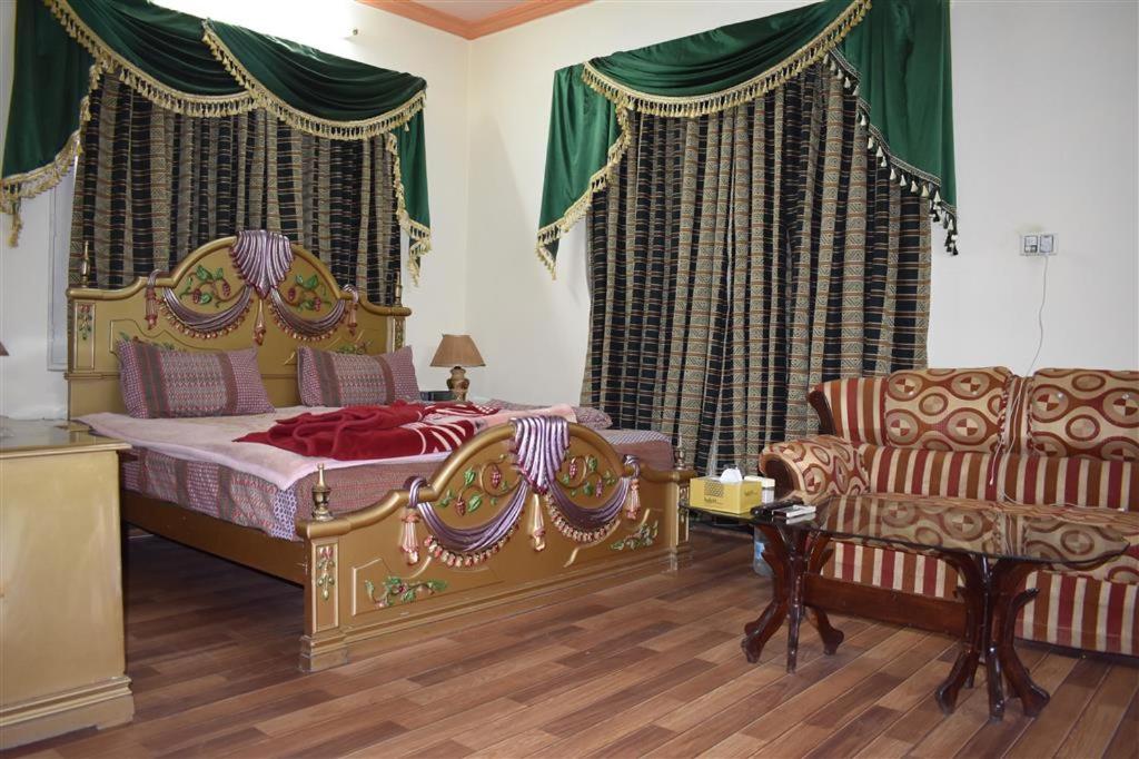 伊斯兰堡Islamabad Lodges的一间卧室配有一张床、一张沙发和一把椅子