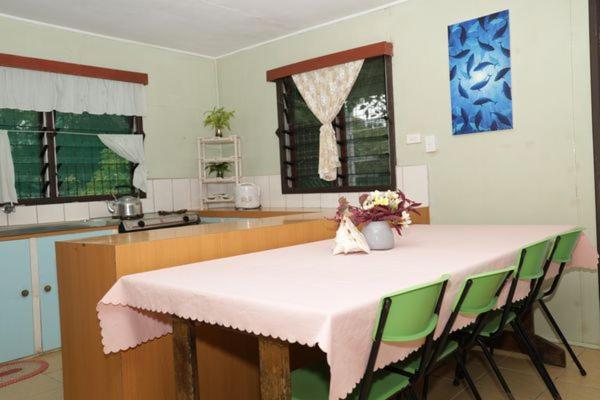 吉佐Gizo Lodge的厨房配有带绿色椅子的桌子和柜台。
