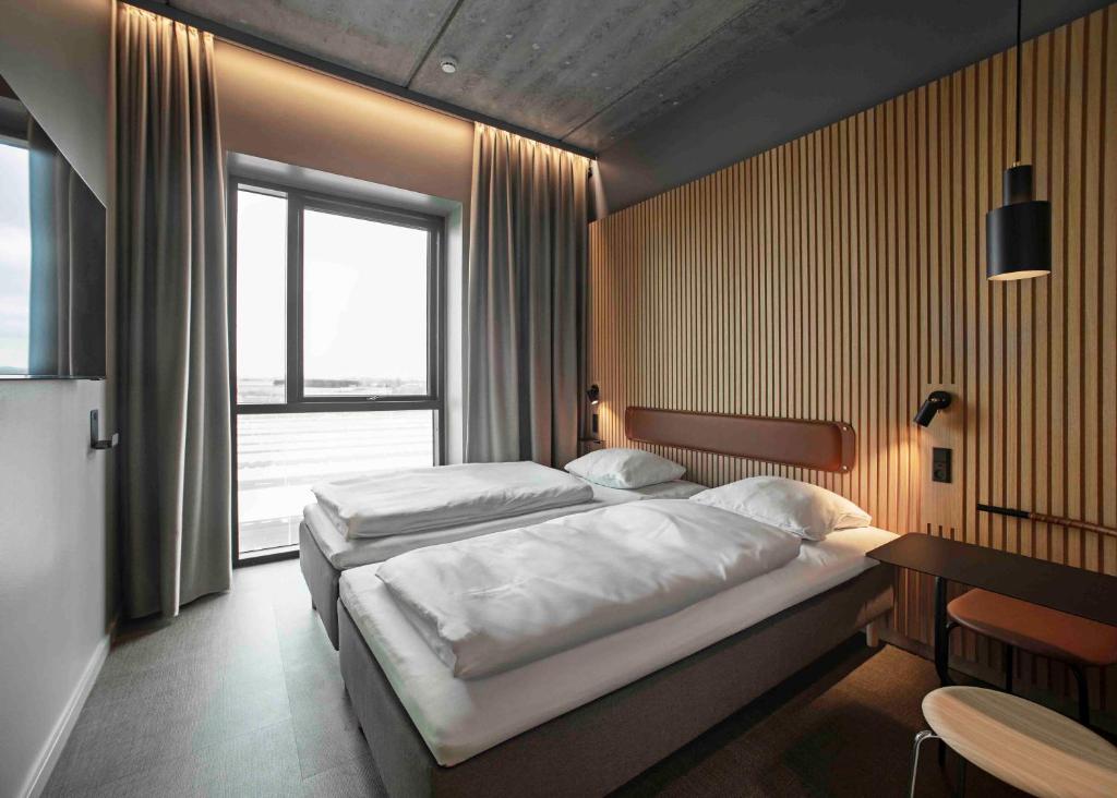 霍森斯Zleep Hotel Horsens的一间卧室设有两张床、一张桌子和一个窗口。