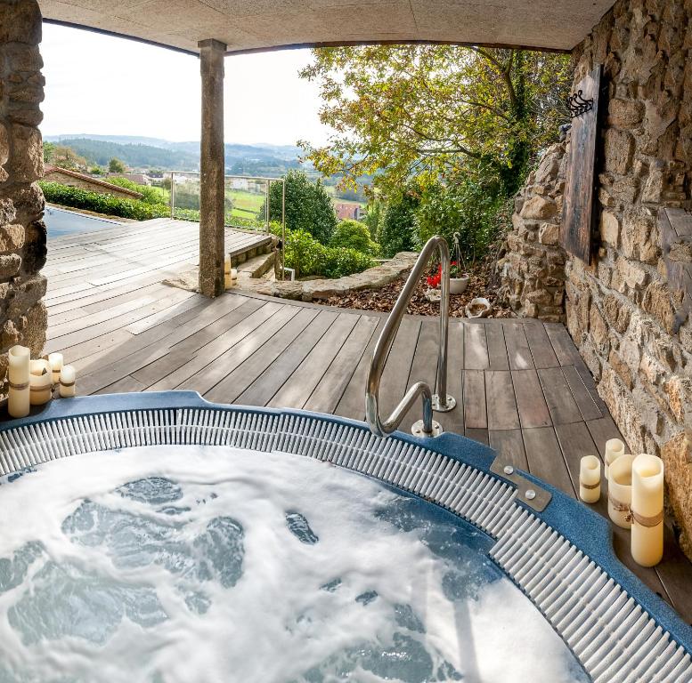 圣地亚哥－德孔波斯特拉Casa do Cebro Casa con piscina y jacuzzi privados的花园内的一个按摩浴缸,设有木制甲板